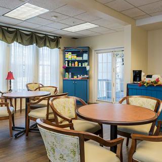 A cozy dining area with round tables and wooden chairs, illuminated by natural light.