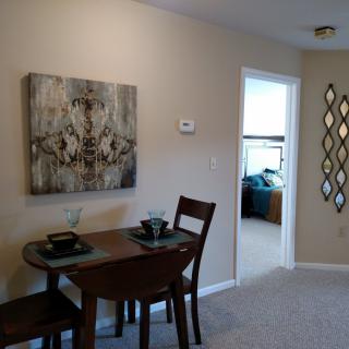 A small dining area featuring a table set with two chairs, adorned with artwork on the wall and a decorative mirror.