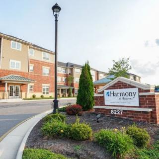 A residential building with a landscaped entrance and a sign labeled 'Harmony.'