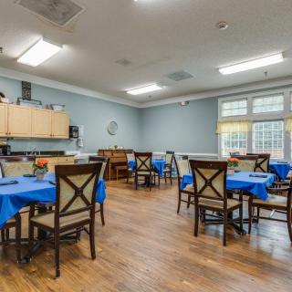 A well-lit dining room with multiple tables and blue tablecloths.