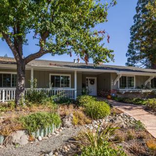 A single-story house with a landscaped front yard featuring a pathway and trees.