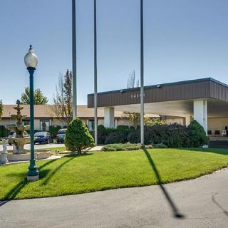 Entrance of a hotel with well-maintained landscaping and flagpoles.