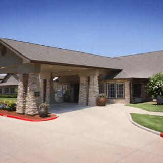 A single-story building with a covered entrance and landscaped surroundings under a clear blue sky.