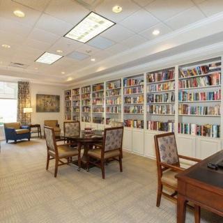 A cozy library with bookshelves, tables, and chairs for reading.