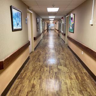 A well-lit hallway featuring wooden flooring and framed artwork along the walls.