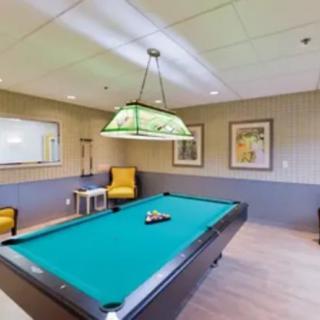 A recreation room featuring a pool table, ambient lighting, and comfortable seating.