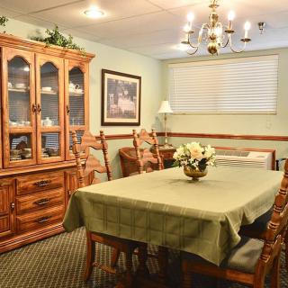 A cozy dining room with a wooden table, chairs, and a china cabinet under a chandelier.