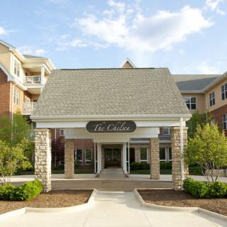 A well-maintained residential building entrance with stone pillars and clear skies.