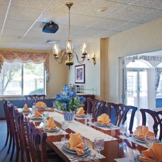 An elegantly set dining room with a long table, floral centerpiece, and chandeliers.