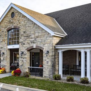 A stone facade building with a front porch and landscaped entrance.