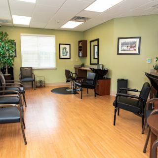 A spacious and inviting waiting room with comfortable chairs, decorative plants, and artwork on the walls.