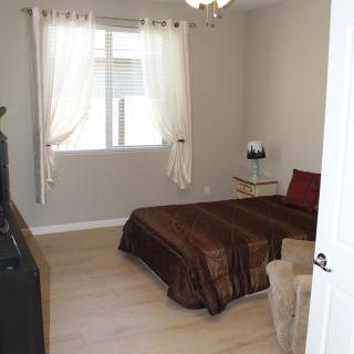 A minimalist bedroom with simple decor, featuring a bed, window with curtains, and a lamp.
