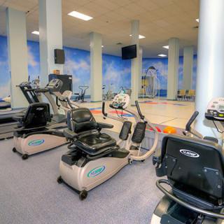 A fitness center with various exercise equipment including treadmills, set in a bright and spacious environment.