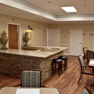 A modern reception area with seating and bar stools, featuring wood flooring and ambient lighting.