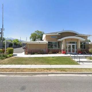 A modern public building with a well-maintained lawn and sidewalk on a clear day.