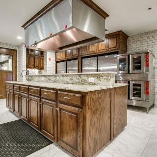 A spacious modern kitchen with wood cabinets, a large island, and stainless steel appliances.