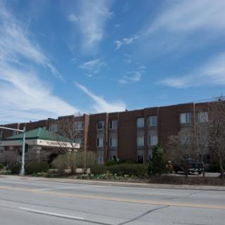 A modern hotel building against a clear blue sky with wispy clouds.