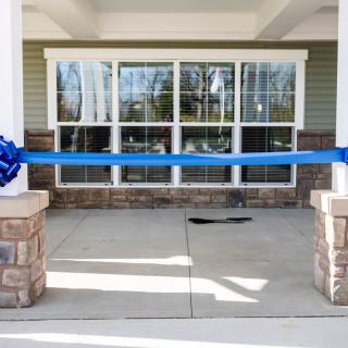 A blue ribbon stretched across a building entrance, prepared for a ribbon-cutting ceremony.