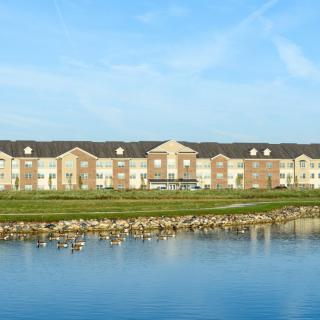A large building with a scenic view across a pond, where geese are seen on the water.