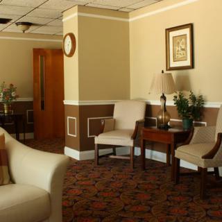 A comfortable waiting room with chairs, tables, and warm lighting.