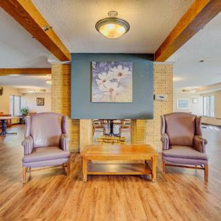 A cozy seating area featuring two armchairs and a wooden table, illuminated by a ceiling light.