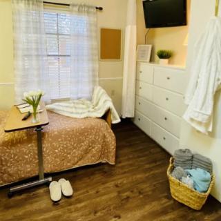 A cozy bedroom with a neatly made bed, wall-mounted television, and soft lighting creates a warm and inviting atmosphere.