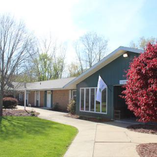A charming building surrounded by lush greenery and vibrant flowers.