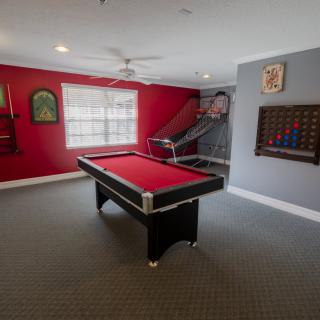 A vibrant game room with a red pool table and decorative wall art.
