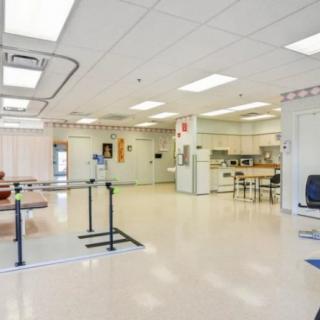 A spacious rehabilitation therapy room equipped with exercise and therapy equipment in a healthcare setting.