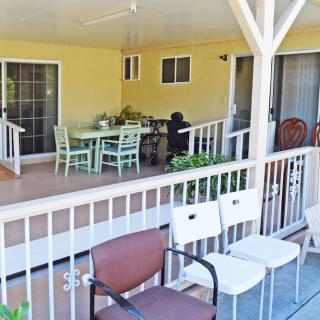 A cozy outdoor patio with a table and chairs, surrounded by a wooden railing.