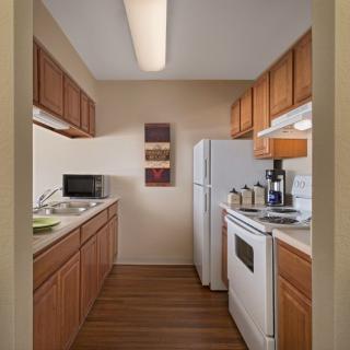 A compact kitchen in an apartment with wooden cabinets and modern appliances.