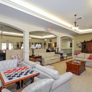 A spacious living room featuring comfortable seating, a coffee table, ceiling lighting, and a checkers game setup.