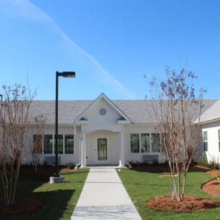 A residential building with a landscaped front yard and a walkway leading to the entrance.