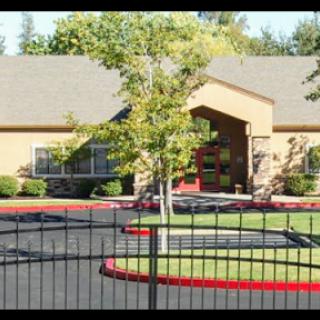 A charming single-story building surrounded by well-maintained landscaping and a secure fence.