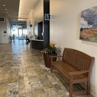 A lobby with a wooden bench, tiled floor, and a reception desk in the background.