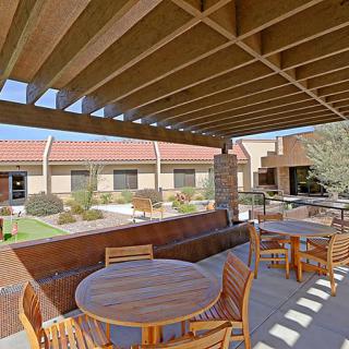 A courtyard with wooden outdoor furniture and a pergola on a sunny day.