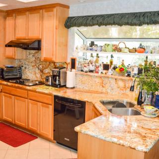 A cozy kitchen with wooden cabinets and a marble countertop, featuring various appliances and decorative items.