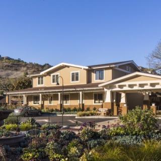 A large suburban house with a well-maintained garden under a clear blue sky.