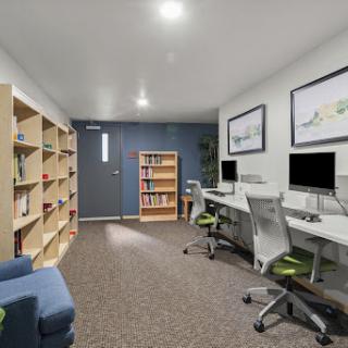 A modern office space featuring computers and bookshelves, designed for productivity and comfort.