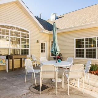 A cozy patio area with a round table, chairs, and an umbrella in a backyard setting.