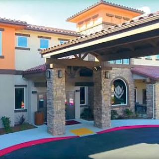 The entrance of a modern building featuring stone pillars and a covered driveway.