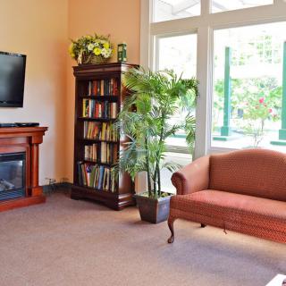 A cozy living room with a bookshelf, sofa, and fireplace.