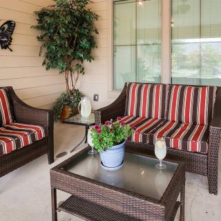 A cozy patio setup with wicker furniture and striped cushions, featuring a small table with a potted plant.