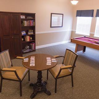 A cozy game room featuring a pool table, bookshelf, and a small table with chairs.