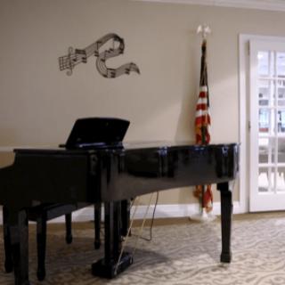 A grand piano in a music room with an American flag and sheet music decor on the wall.