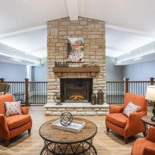 A cozy living room with a stone fireplace, orange chairs, and a wooden table.