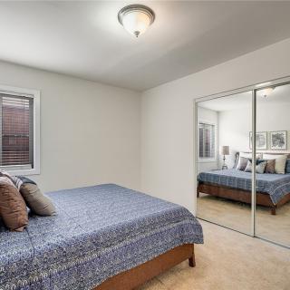 A cozy bedroom featuring a bed with pillows, mirrored closet doors, and a window.