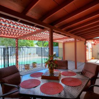 A cozy patio with a dining area overlooking the pool, featuring a covered terrace and outdoor seating.