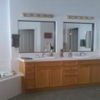 A spacious bathroom featuring a double vanity with mirrors and overhead lighting.