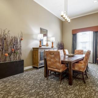 A cozy dining room with a wooden table, upholstered chairs, elegant lighting, and stylish decor.